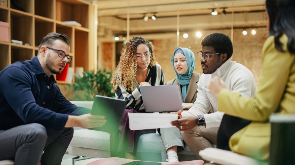 A group of people all working on a single laptop
