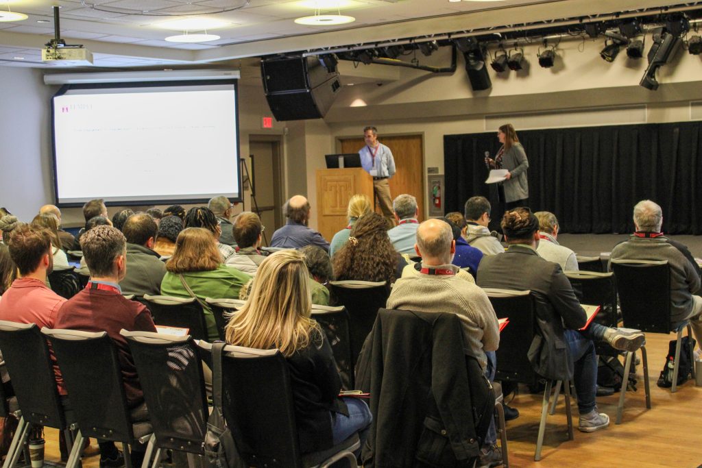 workshop attendees watching stage with 2 presenters