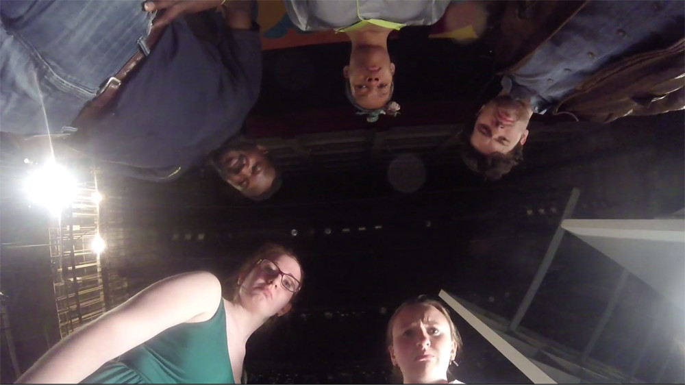 image of 5 people looking at camera from above. Still image from As The Curtain Closes