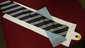 A black and beige striped tie with checkout slip.