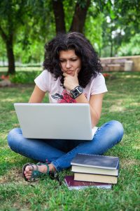 A college girl studying outside on the grass