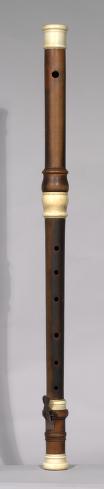 A more sophisticated looking flute made of two pieces of intricately carved wood fitted together with ivory joint pieces.
