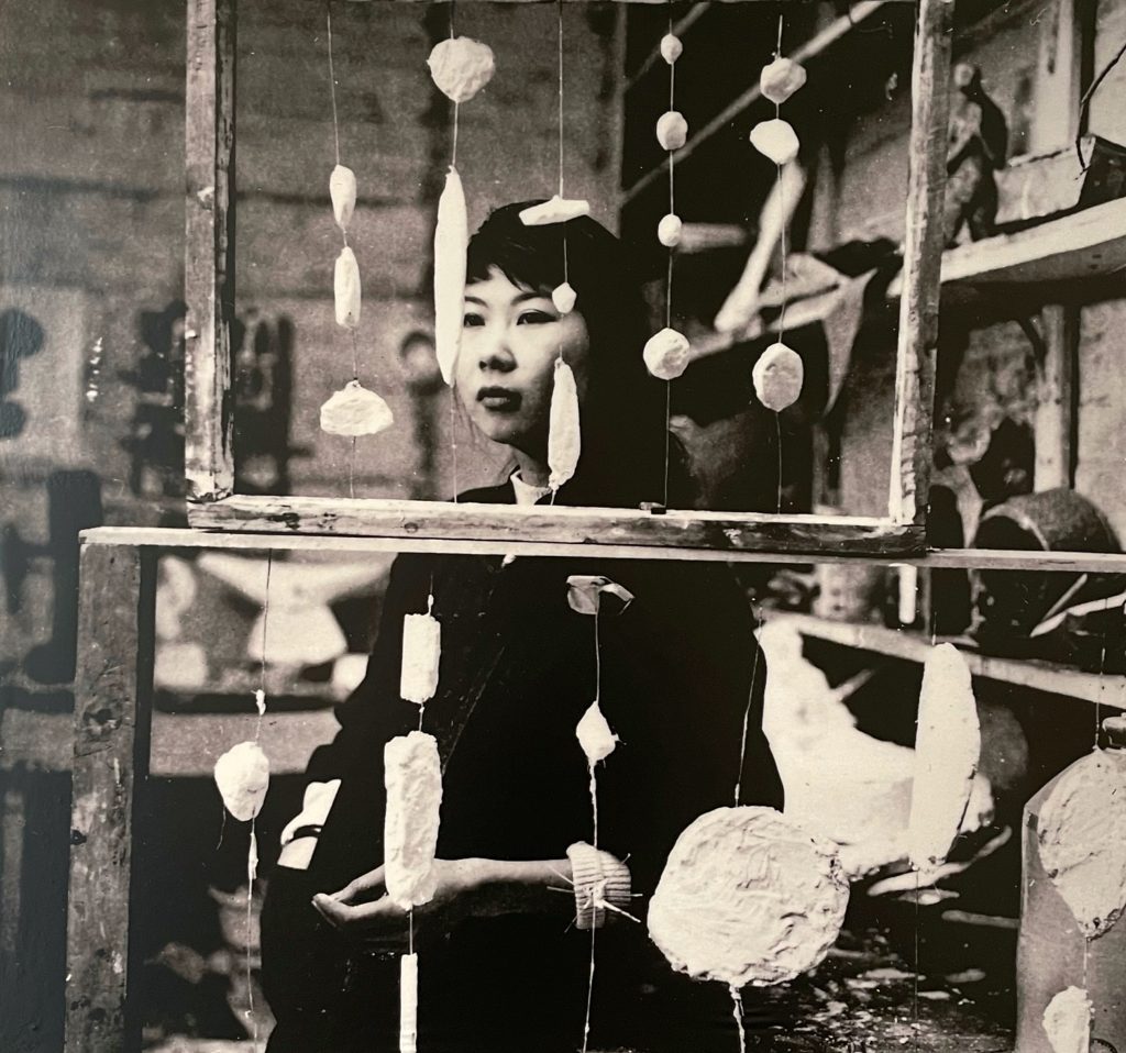 Kim Lim in her studio, standing behind two sculptures titled Abacus, which reference a traditional counting frame in name and form.