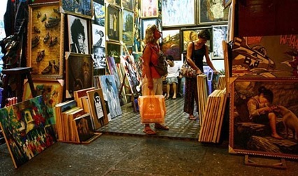 A photo of a store front in Hanoi, Vietnam, selling many paintings.